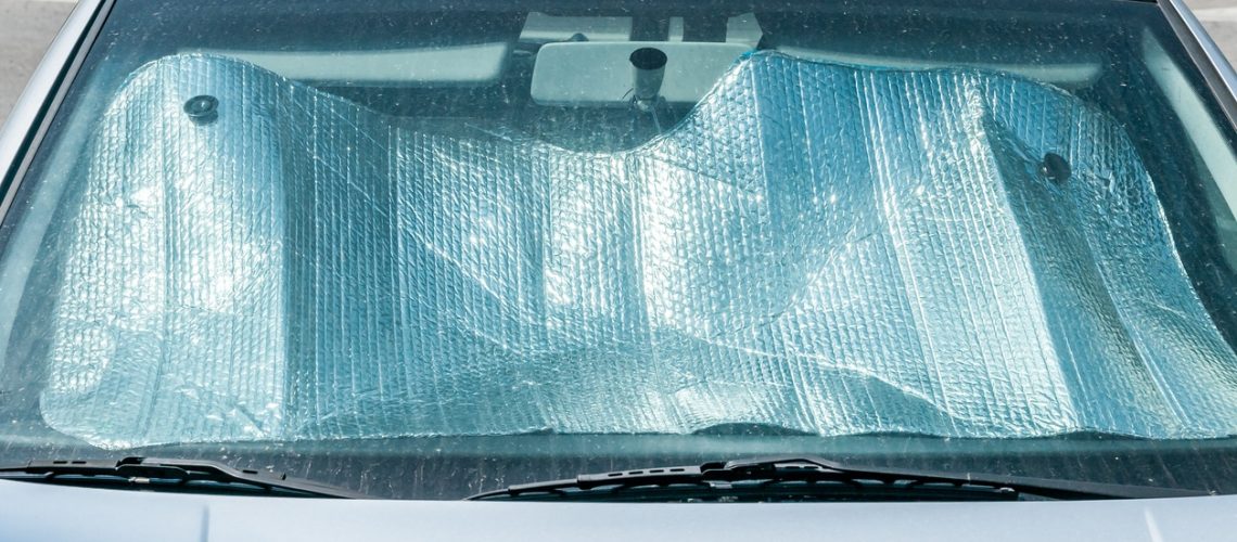 Sun reflector on the windscreen or windshield as protection of the car plastic indoor panel from direct sunlight and heat